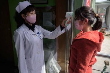 A health worker takes the temperature of a woman amid concerns over the COVID-19 coronavirus, at an entrance of the Pyongchon District People's Hospital in Pyongyang on April 1, 2020. (Photo by KIM Won Jin / AFP)