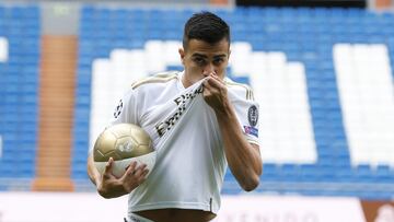 Reinier, vestido de blanco, posa para los medios en el césped del Santiago Bernabéu.