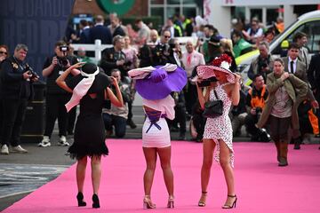 Asistentes a la carrera pasan por la alfombra rosa camino al acceso al hipódromo de Aintree.