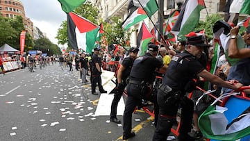 El personal de la Vuelta y agentes de la Ertzaintza de la policía regional vasca mantienen barreras ante los manifestantes propalestinos durante la etapa de hoy.