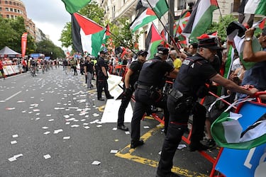 El personal de la Vuelta y agentes de la Ertzaintza de la policía regional vasca mantienen barreras ante los manifestantes propalestinos durante la etapa de hoy. 