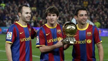 Flanked by Andrés Iniesta (left) and Xavi, Messi holds the 2010 Ballon d'Or aloft.