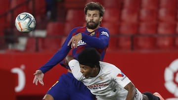 Barcelona's Gerard Pique, left, fights for the ball with Sevilla's Jules Kounde during the Spanish La Liga soccer match between Sevilla and FC Barcelona at the Ramon Sanchez-Pizjuan stadium in Seville, Spain, Friday, June 19, 2020. (AP Photo/Ang