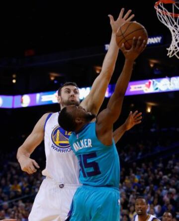 Andrew Bogut bloquea a Kemba Walker.