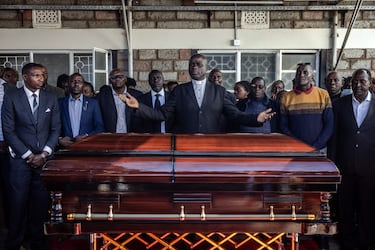 Un sacerdote dirige una oración con miembros de la familia frente al ataúd de Kelvin Kiptum. 