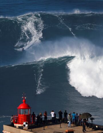 Un grupo de surfistas surcan grandes olas en Praia do Norte, en Nazare (Portugal), con un grupo de aficionados de testigos, fascinados ante la belleza de las vistas y la pericia de los deportistas.