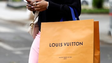 A woman walks with a Louis Vuitton shopping bag in Paris, France, April 17, 2025. REUTERS/Abdul Saboor
