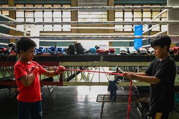 Dos chicos se ayudan en la preparaci¨®n de las manos para la pr¨¢ctica del boxeo.