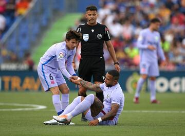 El árbitro Gil Manzano observa como Riqui Puig ayuda a Memphis Depay.