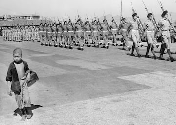 Un niño de nacionalidad china transporta su material de limpiabotas delante de las tropas del 1er Comando Británico.