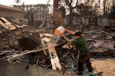 Nancy Belanger vierte agua sobre la propiedad de un vecino, devastada por el fuego, tras el incendio de Palisades en el vecindario de Pacific Palisades en Los Ángeles.