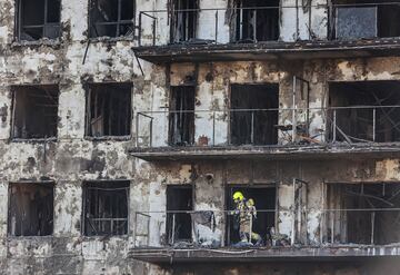 Un agente de la Policía Científica asoma en un balcón del edificio incendiado en Campanar (Valencia).