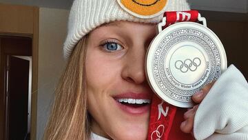 La cara de la snowboarder Julia Marino mirando a cámara y sonriendo mientras se tapa un ojo con la medalla de plata de snowboard slopestyle de los Juegos Olímpicos de Invierno de Pekín 2022, con la cabeza cubierta por un gorro de un smiley.