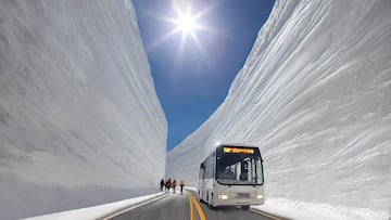Un autobús y varias personas pasando por la Muralla de Nieve de Tateyama, Japón.