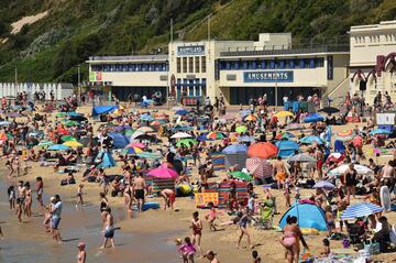 Beachgoers enjoy the sunshine as they sunbathe and play in the sea on Bournemouth beach, southern England, on June 25, 2020. - Just days after lockdown ended and European travel restrictions were lifted, many were staying home in the cool as a heatwave hit the continent with temperatures touching 40 degrees Celcius. Britain was bracing for a flood of visitors to its beaches with the heatwave expected to last until Friday and temperatures set to climb into the mid-30s in the south and centre of the country. (Photo by Glyn KIRK / AFP)