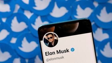 Elon Musk's Twitter profile is seen on a smartphone placed on printed Twitter logo.