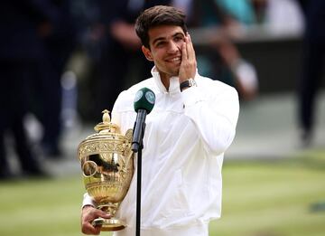 Spain's Carlos Alcaraz holds the winner's trophy as he delivers a speech following his victory against Serbia's Novak Djokovic during their men's singles final tennis match on the fourteenth day of the 2024 Wimbledon Championships at The All England Lawn Tennis and Croquet Club in Wimbledon, southwest London, on July 14, 2024. Defending champion Alcaraz beat seven-time winner Novak Djokovic in a blockbuster final, with Alcaraz winning 6-2, 6-2, 7-6. (Photo by HENRY NICHOLLS / AFP) / RESTRICTED TO EDITORIAL USE