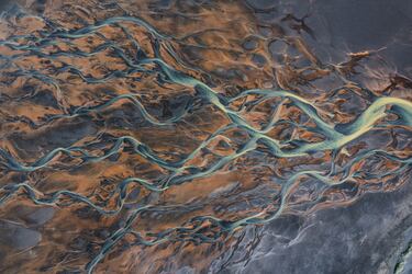 Toma de dron que muestra los canales de un río que fluyen a través de un paisaje volcánico en Islandia.