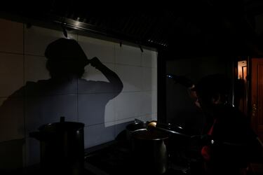 Un cocinero del restaurante de comida casera para llevar "La Cocinona" trabaja en una cocina oscura con la ayuda de las linternas de su teléfono, durante un apagón en Madrid, España.
