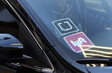 FILE - In this Jan. 12, 2016 file photo, a ride share car displays Lyft and Uber stickers on its front windshield in downtown Los Angeles, Calif. Ride-hailing giants Uber and Lyft have launched subscription plans promising savings for trips to the gym, to work or around town. The ride-hailing companies stand to gain by increasing customer loyalty in a competitive market and securing more predictable revenue at a time when both companies are heading to an initial public offering. (AP Photo/Richard Vogel, File)