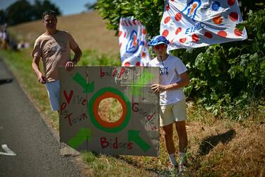 Un espectador se alinea a lo largo de la ruta de la carrera con un objetivo de cartón improvisado para atrapar artículos promocionales ("goodies") distribuidos por la caravana publicitaria del Tour de Francia, así como botellas de hidratación para ciclistas (llamadas "bidones") durante la sexta etapa de la 112.ª edición del Tour de Francia, entre Bayeux y Vire Normandie.