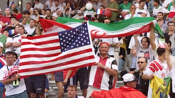 (FILES) In this file photo taken on June 21, 1998, Iranian and American supporters wave their national flags as they cheer for their teams during the France 1998 World Cup football match between Iran and USA at the Gerland stadium in Lyon on June 21, 1998. - Iran and the United States will meet on November 29, 2022 in Qatar, they had marked the memories during the World Cup-1998 with scenes of fraternity between the players of these two rival countries. (Photo by PATRICK KOVARIK / AFP)