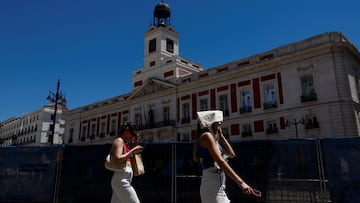 A woman covers her head with a bag as she walks at Puerta del Sol square during a hot day as Spain braces for a heatwave in Madrid, Spain, June 10, 2022. REUTERS/Susana Vera