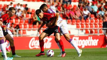 El rojillo Alberto Reina protege el balón ante la presión de un adversario.