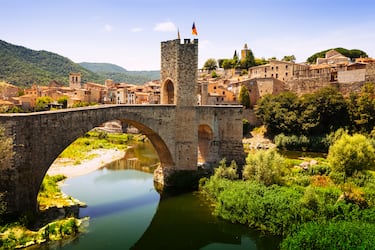 El Puente de Besalú (o Pont Vell) es, sin duda, una de las estructuras más fotogénicas y emblemáticas de Cataluña. Cruzar este puente sobre el río Fluvià es como atravesar un portal temporal hacia el siglo XI. Aunque la primera noticia documentada del puente data del año 1075, la estructura que vemos hoy es el resultado de una historia turbulenta llena de destrucciones y renacimientos.