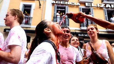 Una asistente al "Chupinazo" bebe vino durante la fiesta ininterrumpida en el famoso festival de encierros de toros de Pamplona.