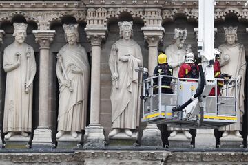 Varios bomberos trabajan en un elevador junto a la fachada de la catedral de Notre Dame