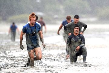 El jugador neozelandés del Northland y de los Blues Mud Run de Super Rugby, Tom Robinson (izquierda), vadea a través del agua y el barro durante la marea baja en la Bahía de Ngataringa. La imagen corresponde a una intensa sesión de entrenamiento de los Blues en la Base Naval de Devonport en Auckland, Nueva Zelanda.