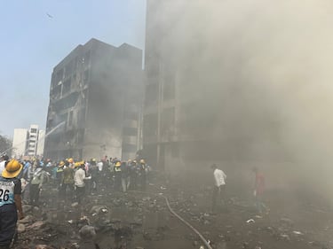 Los miembros del equipo de rescate trabajan mientras el humo se eleva en el lugar donde se estrelló un avión de Air India en Ahmedabad.