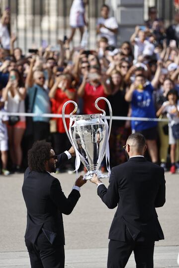 Los capitanes del Real Madrid Marcelo (i) y Karim Benzema (d) muestran a los aficionados el trofeo a la salida de la Catedral de la Almudena.