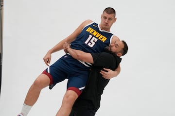 Nikola Jokic es levantado por Claus Antunes, uno de los preparadores de los Nuggets.