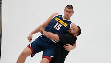 Nikola Jokic es levantado por Claus Antunes, uno de los preparadores de los Nuggets.