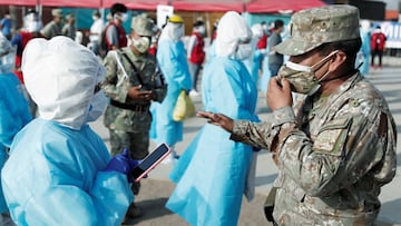 A soldier talks to a healthcare worker wearing personal protective equipment (PPE) at Cantagallo, an indigenous Shipibo-Conibo community, before the kick off of the vaccination campaign against the coronavirus disease (COVID-19), in Lima, Peru February 19, 2021. REUTERS/Angela Ponce