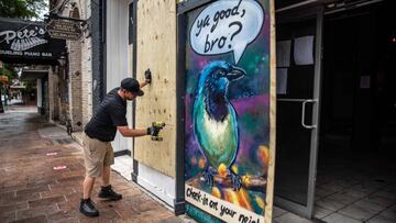 A worker drills plywood boards over windows and doors of a bar in Austin, Texas, June 26, 2020. - Texas Governor Greg Abbott ordered bars to be closed by noon on June 26 and for restaurants to be reduced to 50% occupancy. Coronavirus cases in Texas have s