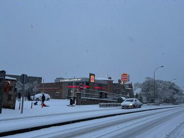 Un coche trata de seguir su camino en una carretera nevada en  Galapagar, municipio de la sierra madrileña.