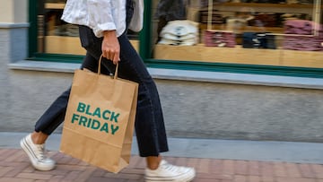 Moving image of a girl walking hurriedly with a shopping bag in front of a shop window. Shopping day, bargains, black friday.