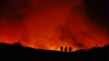 Siluetas de personas mientras arde un incendio forestal en Puercas, España.