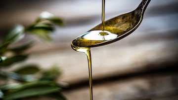 Pouring extra virgin olive oil on a vintage metal spoon. Selective focus on spoon. Useful copy space available for text and/or logo. Predominant colors are gold, green and brown. High resolution 42Mp studio digital capture taken with Sony A7rii and Sony FE 90mm f2.8 macro G OSS lens
