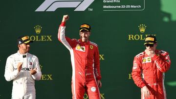 Ferrari's German driver Sebastian Vettel (C) celebrates his victory on the podium next to second-placed Mercedes' British driver Lewis Hamilton (L) and third-placed Ferrari's Finnish driver Kimi Raikkonen (R) after the Formula One Australian Grand Prix in Melbourne on March 25, 2018. / AFP PHOTO / WILLIAM WEST / -- IMAGE RESTRICTED TO EDITORIAL USE - STRICTLY NO COMMERCIAL USE --