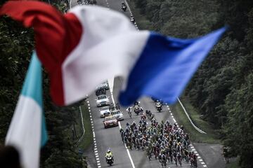 El pelotón bajo una bandera nacional francesa sostenida por un aficionado asistente.