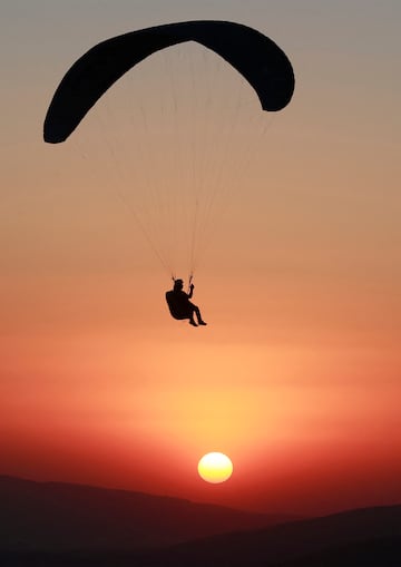 Un miembro del equipo de parapente de Sulaymaniyah se desliza bajo la puesta de sol después de un lanzamiento desde el Monte Azmar sobre la ciudad de Sulaymaniyah, en el noreste de Irak.