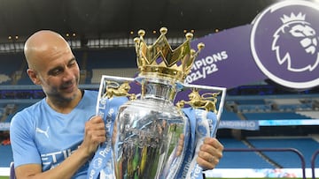 TOPSHOT - Manchester City's Spanish manager Pep Guardiola celebrates with the Premier league trophy on the pitch after the English Premier League football match between Manchester City and Aston Villa at the Etihad Stadium in Manchester, north west England, on May 22, 2022. - Manchester City won the Premier League for the fourth time in five seasons after a pulsating title race reached a dramatic conclusion as the champions staged an incredible comeback from two goals down to beat Aston Villa 3-2 on Sunday. (Photo by Oli SCARFF / AFP) / RESTRICTED TO EDITORIAL USE. No use with unauthorized audio, video, data, fixture lists, club/league logos or 'live' services. Online in-match use limited to 120 images. An additional 40 images may be used in extra time. No video emulation. Social media in-match use limited to 120 images. An additional 40 images may be used in extra time. No use in betting publications, games or single club/league/player publications. / 