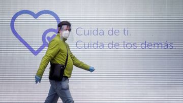 Un hombre camina con mascarilla, guantes y pantalla protectora por una calle del centro de A Coruña.