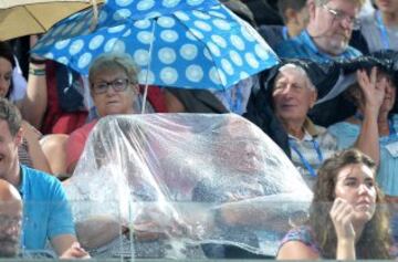 Los espectadores se protegen de la lluvia en el torneo de tenis de Brisbane.