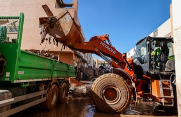 Un tractor retirando restos de las inundaciones  en un camión, en Alfafar, Valencia.