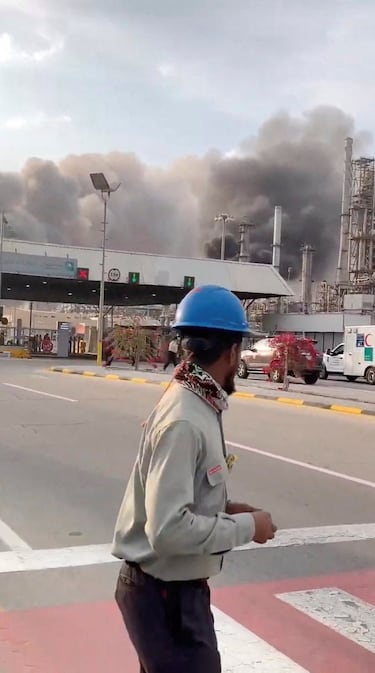 Trabajadores evacúan el área alrededor de la refinería mientras el humo se eleva tras un presunto ataque con drones iraníes, en Ras Tanura, Arabia Saudita.